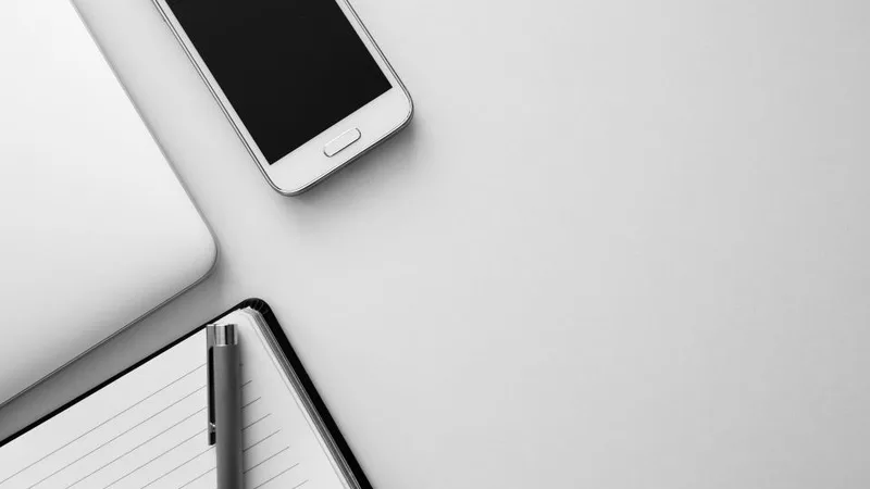 Smartphone and notebook on a white desk