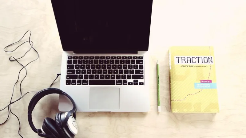 Laptop, headphones and a book on a desk