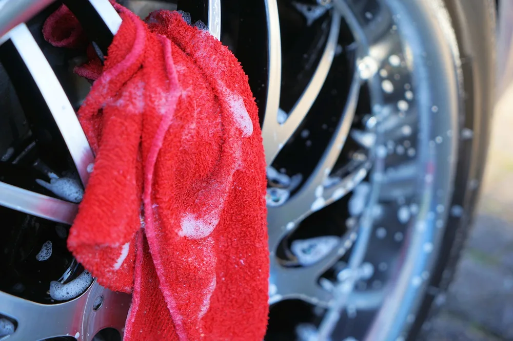 Car wheel being cleaned with a microfiber cloth